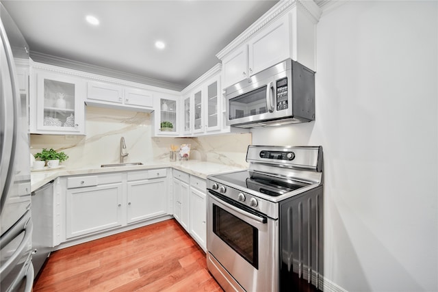 kitchen featuring appliances with stainless steel finishes, light hardwood / wood-style floors, white cabinetry, and sink