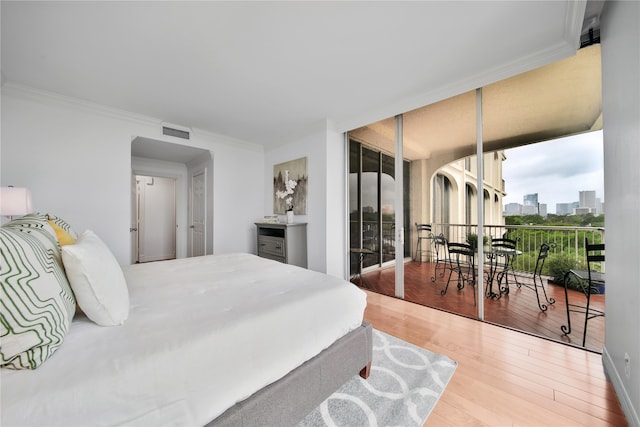 bedroom featuring expansive windows, ornamental molding, and hardwood / wood-style flooring