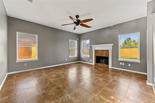 unfurnished living room with dark tile patterned floors, plenty of natural light, and ceiling fan