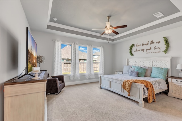 carpeted bedroom featuring a raised ceiling and ceiling fan