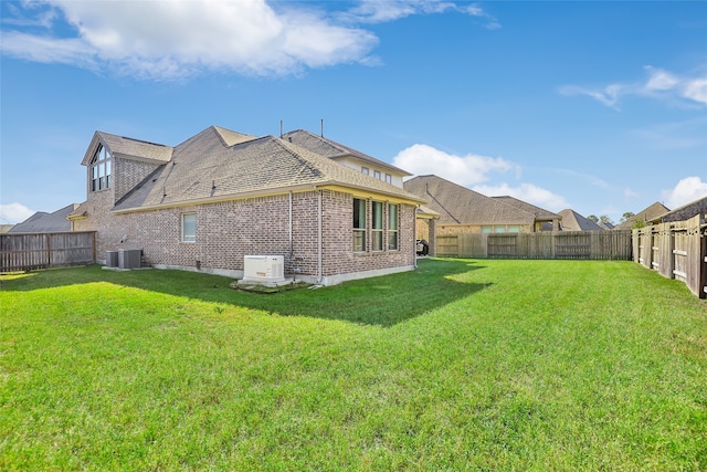 rear view of house featuring a lawn and central AC