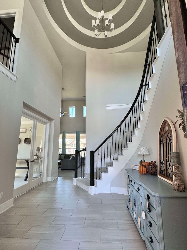 entrance foyer featuring a raised ceiling, light wood-type flooring, a high ceiling, and an inviting chandelier