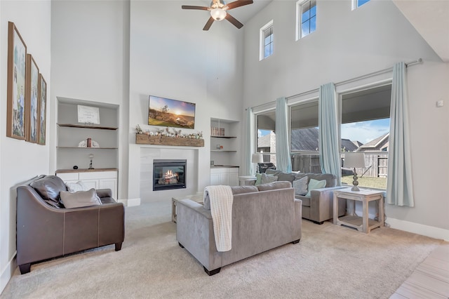 carpeted living room with built in features, a healthy amount of sunlight, and a high ceiling