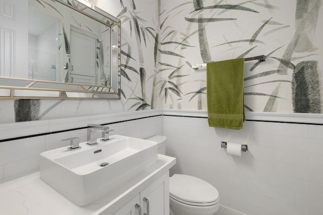 bathroom featuring vanity, toilet, and tile walls