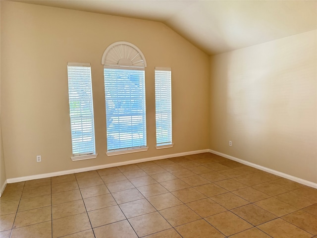 empty room with plenty of natural light, light tile patterned flooring, and lofted ceiling