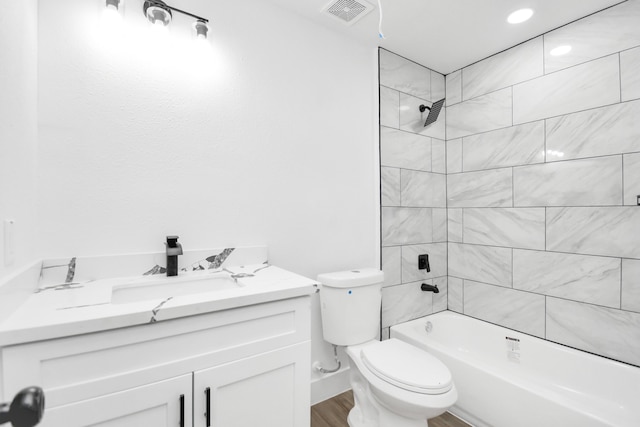 full bathroom featuring hardwood / wood-style floors, vanity, toilet, and tiled shower / bath