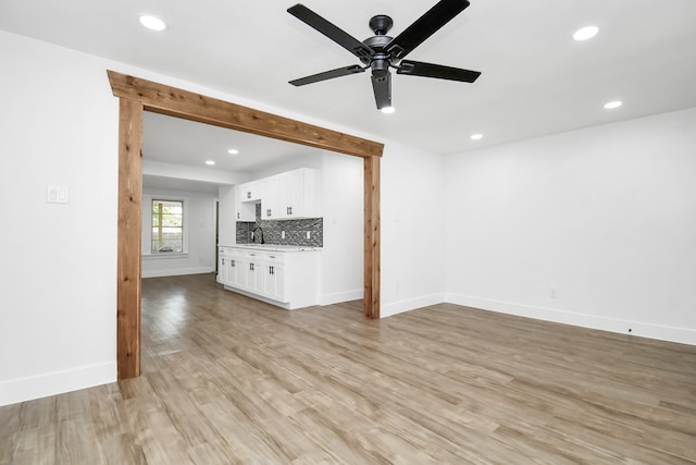 unfurnished living room with ceiling fan, sink, and light hardwood / wood-style flooring