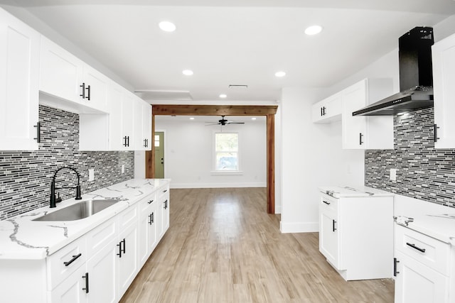 kitchen featuring white cabinets, light wood-type flooring, wall chimney exhaust hood, and sink