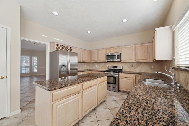 kitchen featuring tasteful backsplash, stainless steel appliances, sink, light brown cabinets, and a kitchen island