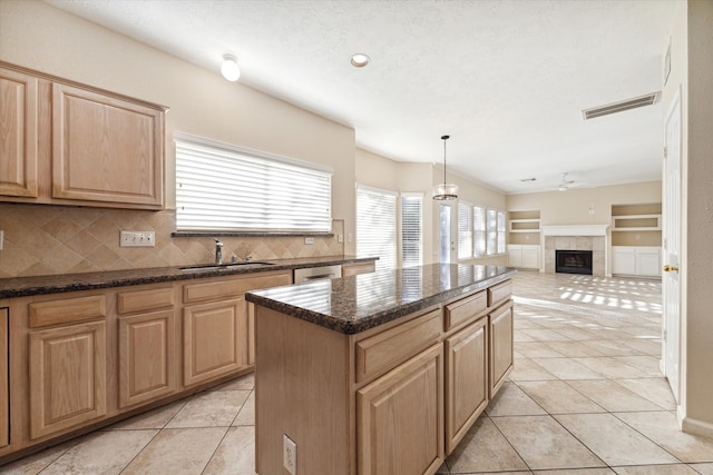 kitchen with tasteful backsplash, decorative light fixtures, a fireplace, a center island, and light tile patterned flooring