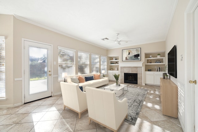 living room featuring built in shelves, ceiling fan, a fireplace, and a healthy amount of sunlight