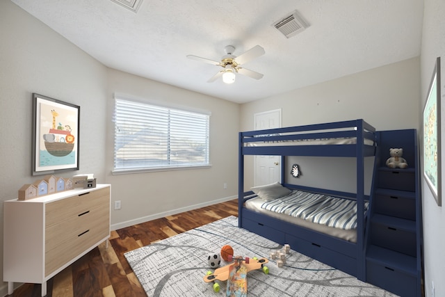 bedroom with a textured ceiling, ceiling fan, and dark hardwood / wood-style floors