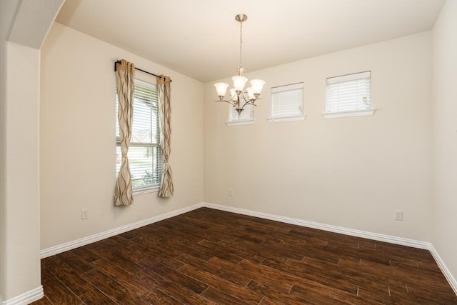 spare room featuring dark hardwood / wood-style flooring, plenty of natural light, and a chandelier