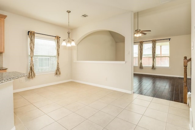 unfurnished dining area with ceiling fan with notable chandelier and light wood-type flooring