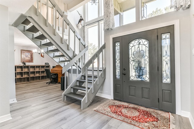 foyer entrance with plenty of natural light, light hardwood / wood-style floors, and a towering ceiling