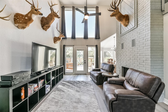 living room featuring ceiling fan, hardwood / wood-style floors, and a towering ceiling