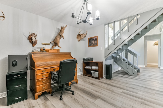 office area with light wood-type flooring, a textured ceiling, and a chandelier