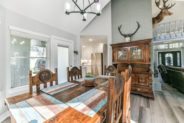 dining area with light hardwood / wood-style flooring, high vaulted ceiling, and a notable chandelier