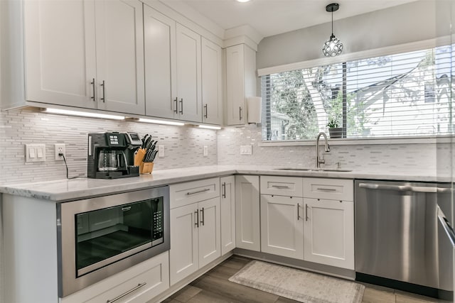 kitchen with white cabinetry, built in microwave, dishwasher, sink, and decorative light fixtures