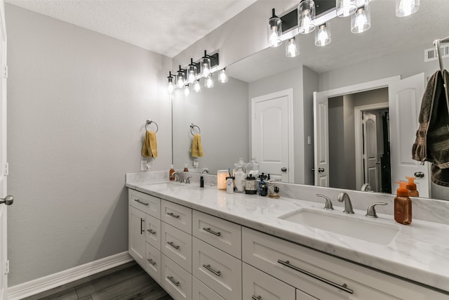 bathroom with hardwood / wood-style floors, vanity, and a textured ceiling