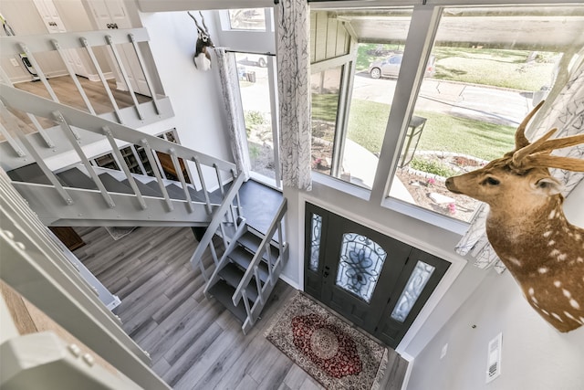 stairway with a healthy amount of sunlight, wood-type flooring, and a towering ceiling