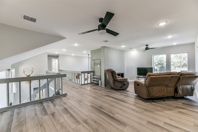 living room with ceiling fan, a fireplace, and light wood-type flooring