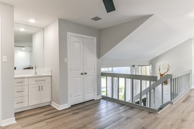 corridor featuring light hardwood / wood-style floors, sink, and vaulted ceiling