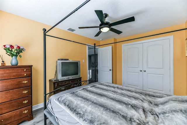 bedroom with ceiling fan, a barn door, and light wood-type flooring