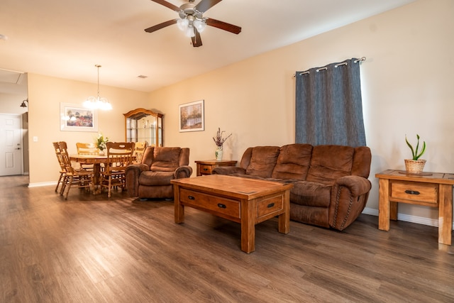 living room with dark hardwood / wood-style flooring and ceiling fan with notable chandelier