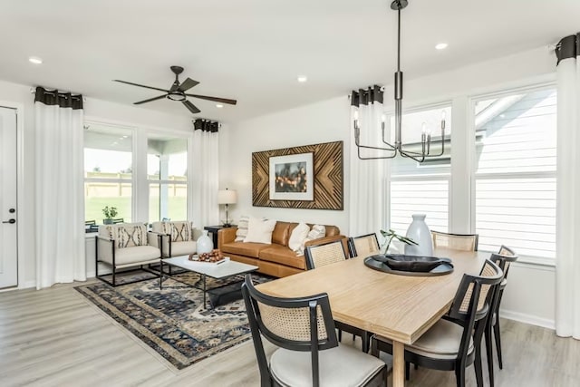 dining area featuring light wood-type flooring and ceiling fan with notable chandelier