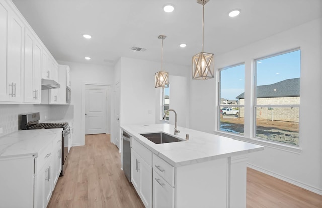 kitchen featuring white cabinetry, sink, stainless steel appliances, and decorative light fixtures