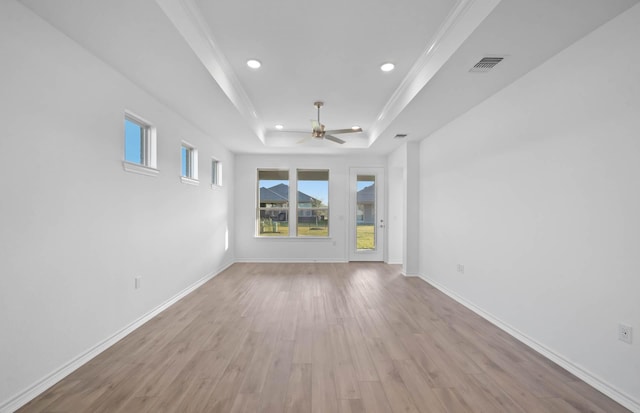 spare room with ceiling fan, ornamental molding, light hardwood / wood-style flooring, and a tray ceiling