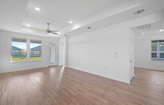 spare room featuring ceiling fan, a raised ceiling, crown molding, and light hardwood / wood-style flooring