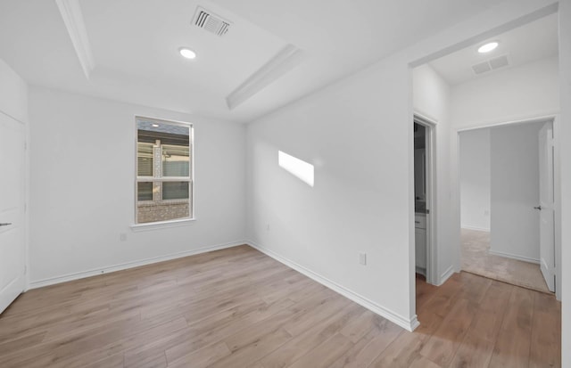 empty room with a raised ceiling and light wood-type flooring