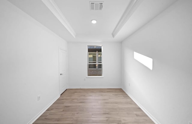 spare room featuring light hardwood / wood-style floors, a raised ceiling, and crown molding