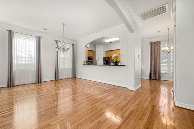 unfurnished living room featuring crown molding, light hardwood / wood-style flooring, sink, and an inviting chandelier