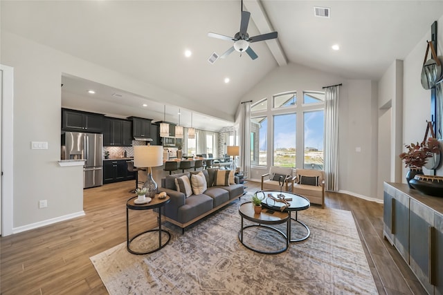 living room featuring beam ceiling, light hardwood / wood-style floors, high vaulted ceiling, and ceiling fan