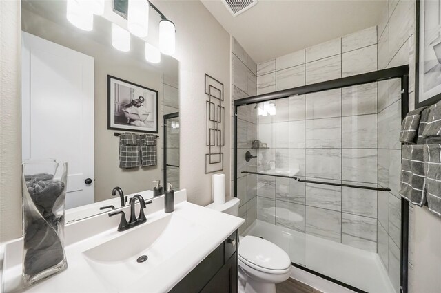 bathroom featuring vanity, a shower with shower door, and toilet