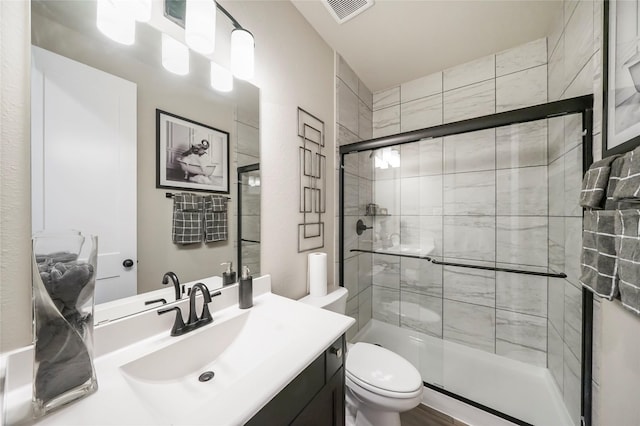 bathroom featuring vanity, toilet, and an enclosed shower