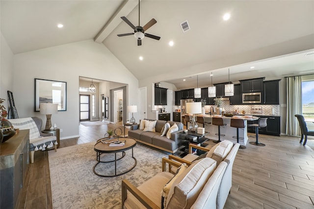 living room featuring ceiling fan, beamed ceiling, and high vaulted ceiling