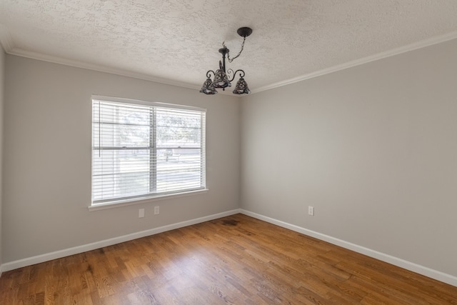 spare room featuring wood-type flooring, a textured ceiling, ornamental molding, and a notable chandelier