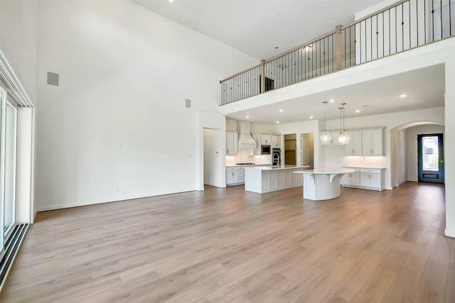 9923 Hunters Run Dr, Missouri City, TX 77459 - unfurnished living room with a high ceiling, arched walkways, light wood-style flooring, a baseboard heating unit, and recessed lighting