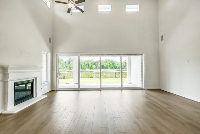 9923 Hunters Run Dr, Missouri City, TX 77459 - unfurnished living room with a towering ceiling, ceiling fan, a glass covered fireplace, and wood finished floors