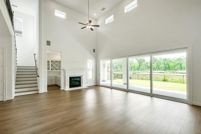 9923 Hunters Run Dr, Missouri City, TX 77459 - unfurnished living room with a high ceiling, healthy amount of natural light, a ceiling fan, stairway, and a glass covered fireplace