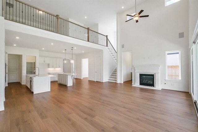 9923 Hunters Run Dr, Missouri City, TX 77459 - unfurnished living room featuring a towering ceiling, wood finished floors, a ceiling fan, a glass covered fireplace, and recessed lighting