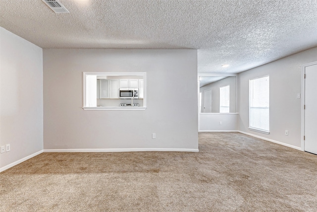 carpeted empty room featuring a textured ceiling