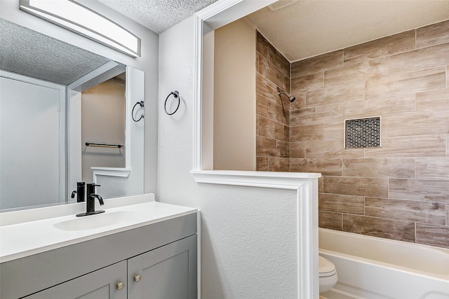 full bathroom featuring toilet, vanity, a textured ceiling, and tiled shower / bath