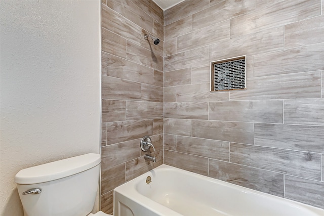 bathroom with toilet and tiled shower / bath