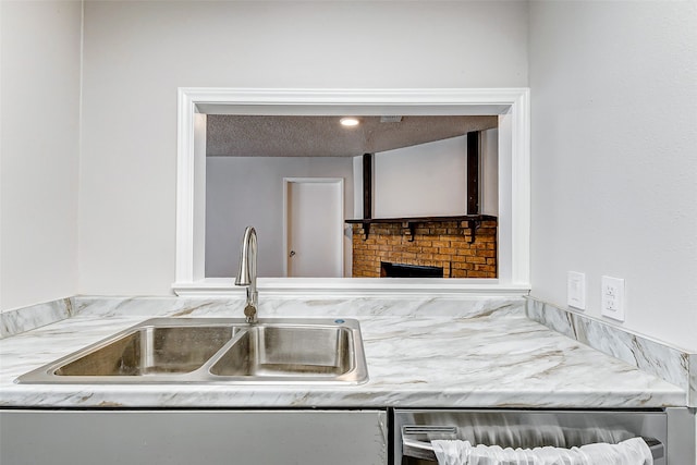 kitchen featuring a textured ceiling, a fireplace, sink, and beverage cooler