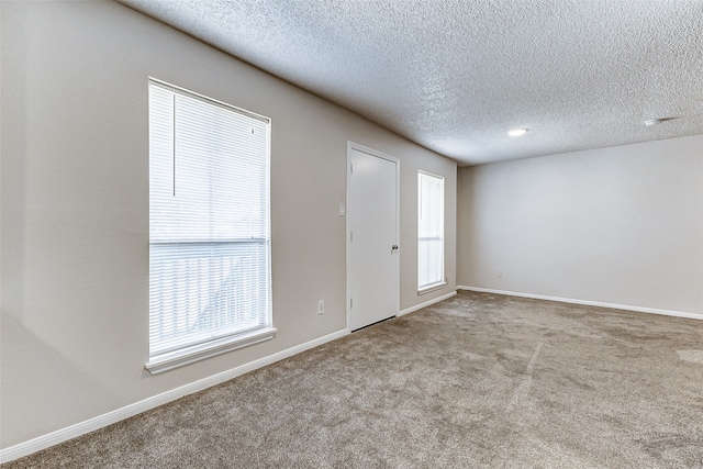 carpeted spare room featuring a textured ceiling